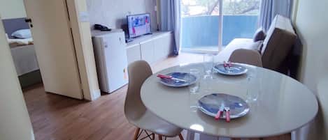 A dining area with a round table, chairs, and a television on a cabinet.