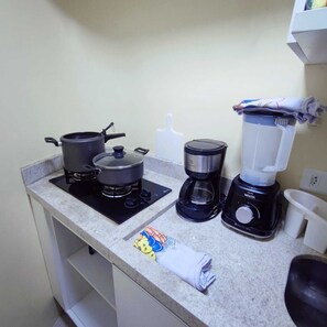 Una cuina amb fogó, cafetera i batedora damunt el taulell.