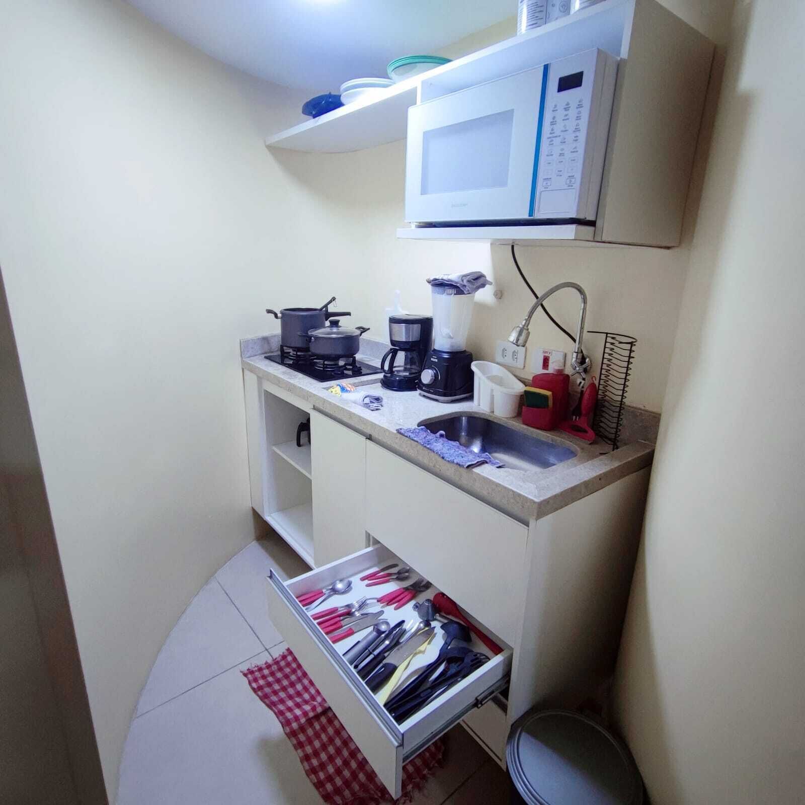 Een gezellige, compacte kitchenette met een magnetron, fornuis, koffiezetapparaat en een klein spoelgedeelte.