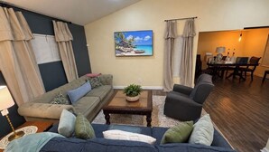Una sala de estar con sofá, sillones, una mesa de centro y un comedor con mesa y sillas.