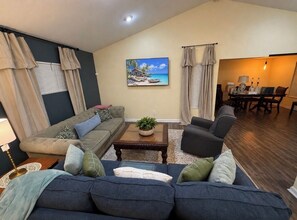Un salon comprenant un canapé, des fauteuils, une table basse et un coin repas avec une table et des chaises.