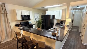 Una cocina moderna con una isla central, taburetes de bar, un refrigerador y un microondas.