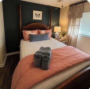 A neatly made bed with a headboard, a bedside lamp, and a framed picture on the wall.