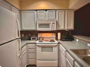 A kitchen with white cabinets, a stove, a microwave, and a sink. - Tally Townhome Minutes from FAMU & FSU (Tallahassee)