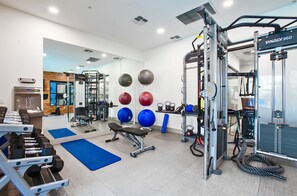 Et fitnesscenter med forskellig træningsudstyr, herunder bænkpres, kettlebells og et squat rack.