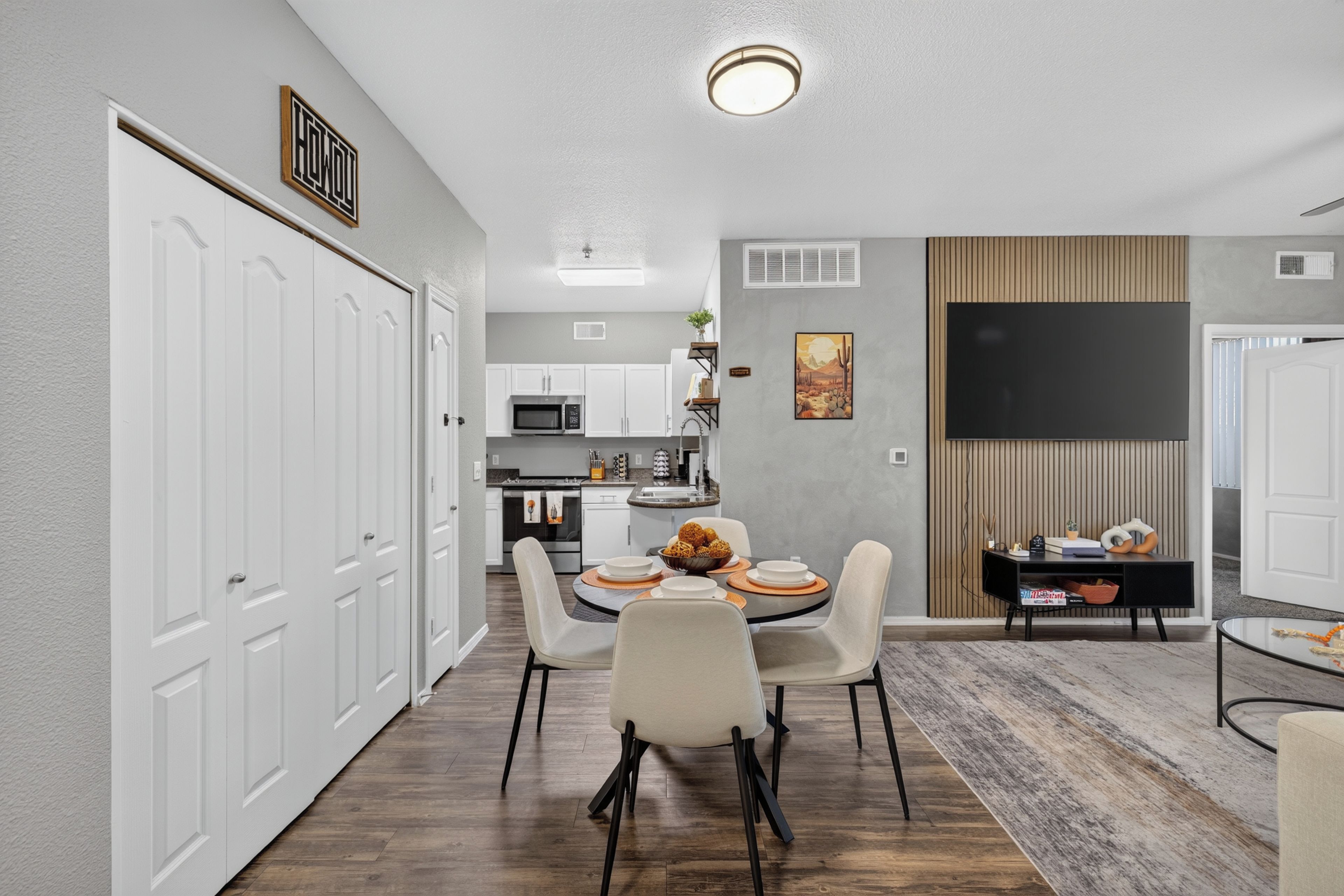 A modern kitchen with white cabinets, a microwave, and a dining area with a table set for four.