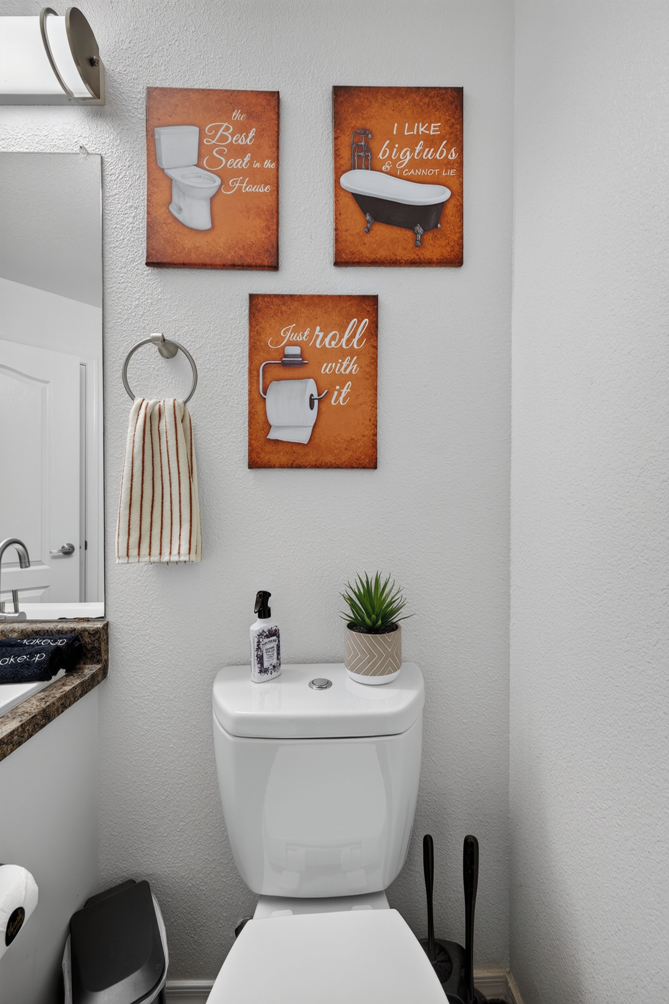 A bathroom with a toilet, a towel rack, and three wall-mounted signs with humorous text.