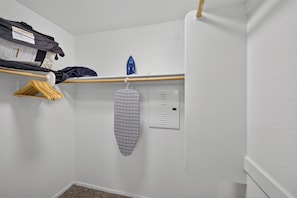 A laundry area with a hanging iron, a clothes rack with folded garments, and a shelf with folded clothes and a package. - Tranquil Escape Pool-Gym-Free Parking 1st Floor (Phoenix)