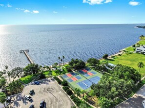 A coastal property with a tennis court, parking area, and a view of the sea. - Waterfront 2BR, Water Views, Beach Access, Pool (Ruskin)