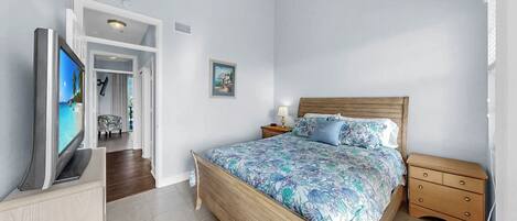 A bedroom with a bed, a TV, a nightstand, and a dresser.