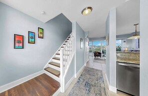 Ein modernes Interieur mit einer Treppe, einer Küchenzeile und Blick durch eine Glastür.