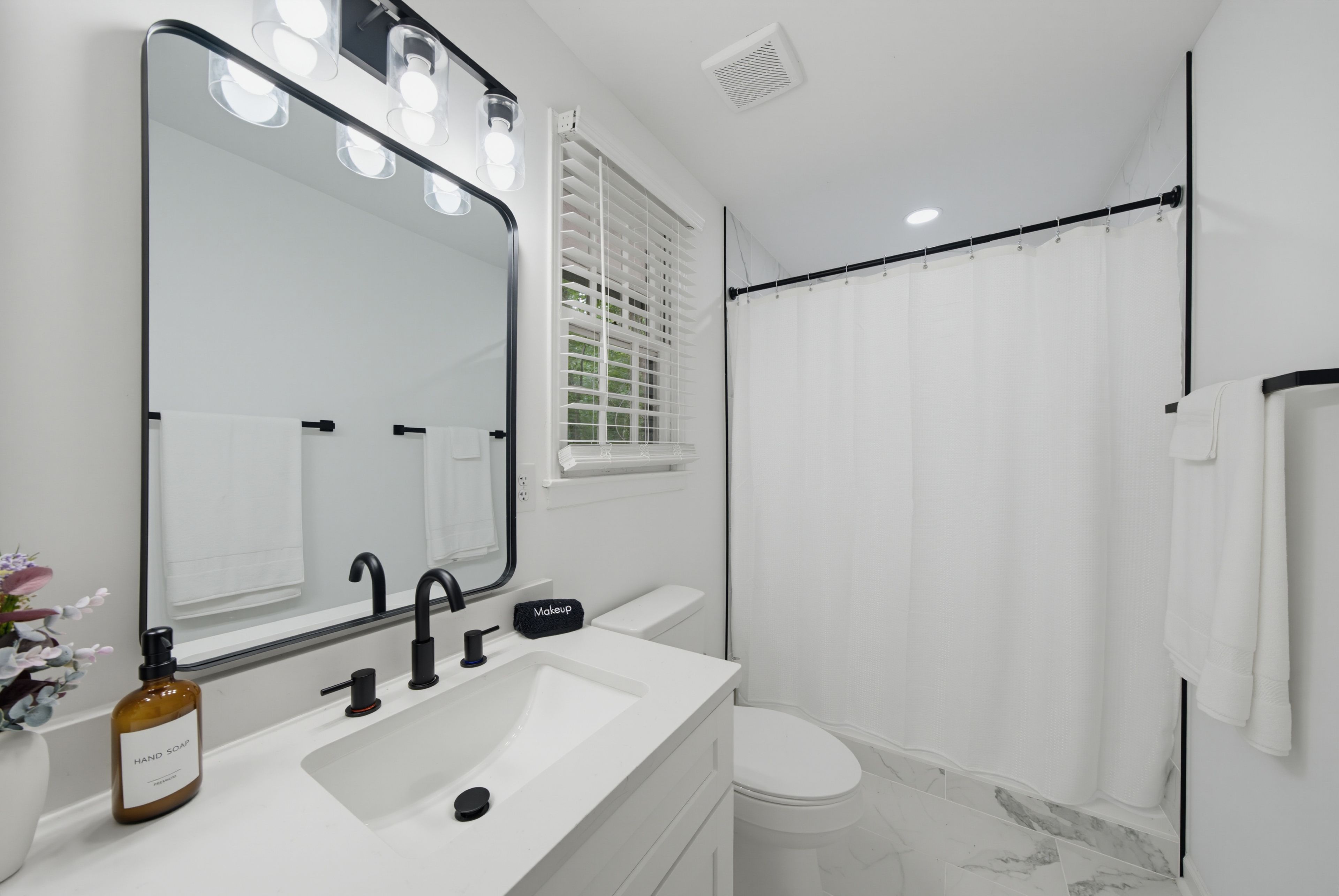 Une salle de bain moderne avec un grand miroir, un lavabo, des toilettes et un espace douche.