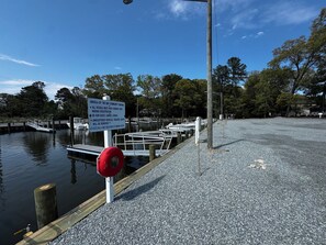 A marina with boats docked, a gravel dock, and a sign with marina rules. - Stylish home w all the comforts in a bay front community near beaches & shopping (Lewes)