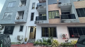 A multi-story residential building with balconies, air conditioning units, and a red-tiled entrance. - 4 Bed Luxury Town House (Lagos)