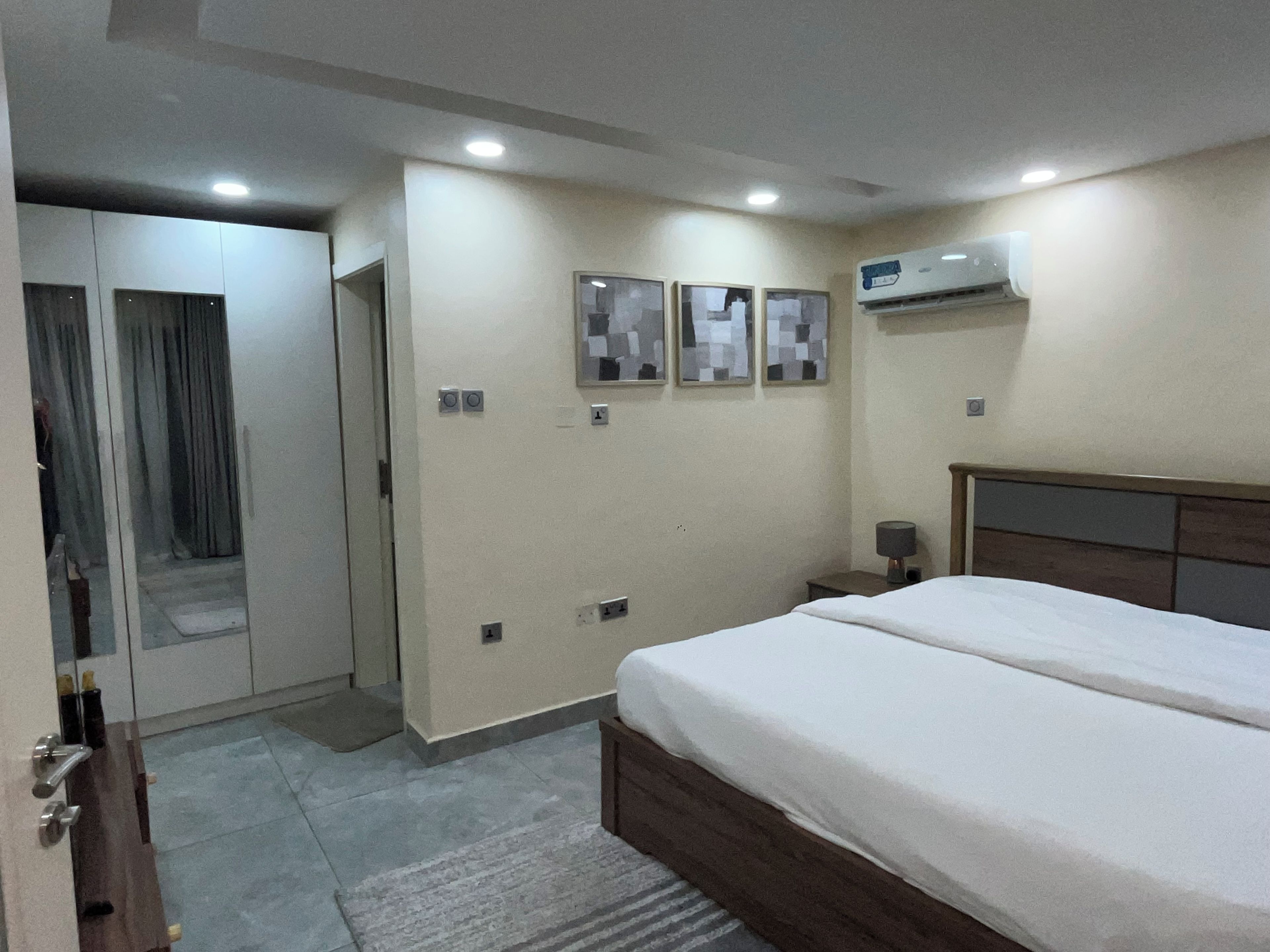 Una habitación de hotel con cama, armario, espejo y aire acondicionado.