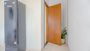 Ein Flur mit einem Kühlschrank, einer Holztür und einem Blumentopf.