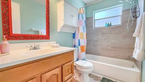 A bathroom with a white bathtub, a toilet, and a shower with a colorful curtain. - Cozy home New Port Richey (New Port Richey)