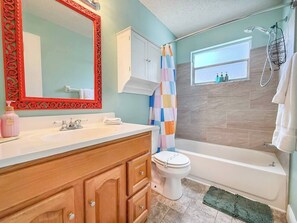 Une salle de bain avec une baignoire blanche, des toilettes et une douche agrémentée d’un rideau coloré.