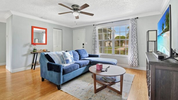 A living room with a sectional sofa, a ceiling fan, a television, and a large window with curtains. - Cozy home New Port Richey (New Port Richey)