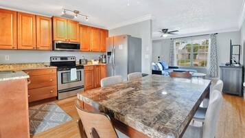 A modern kitchen with wooden cabinets, stainless steel appliances, and a marble countertop.
