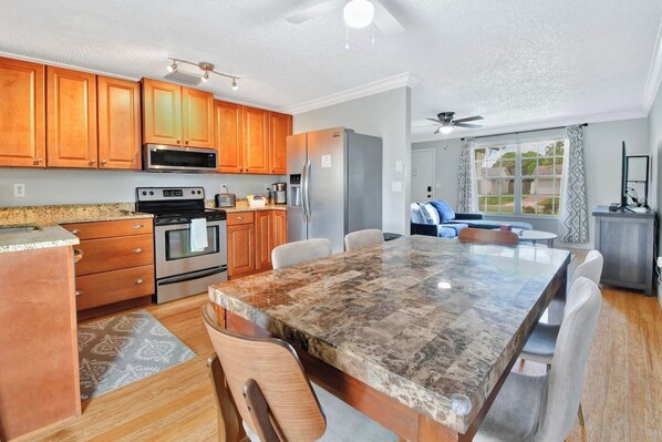 A modern kitchen with wooden cabinets, stainless steel appliances, and a marble countertop.