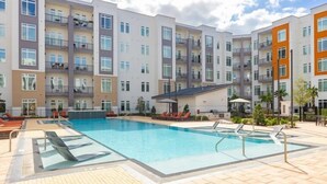 Un edificio residenziale a più piani con piscina e area salotto all'aperto.