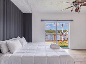 A bedroom with a bed, a ceiling fan, and a view of a lake through a sliding glass door. - Newly Renovated, Waterfront, 2-bedroom in Hollywood! (Hollywood)