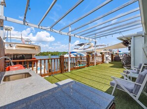 A covered outdoor area with a pool, lounge chairs, and a view of boats. - Newly Renovated, Waterfront, 2-bedroom in Hollywood! (Hollywood)