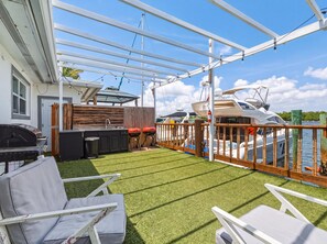 A covered outdoor patio with artificial grass, a barbecue grill, and a view of boats on the water. - Newly Renovated, Waterfront, 2-bedroom in Hollywood! (Hollywood)