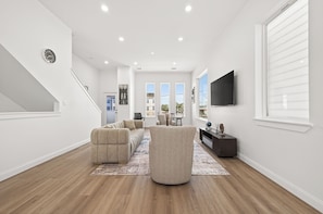 Ein modernes Wohnzimmer mit einem Ecksofa, einem runden Hocker und einem flachbildfernseher an der Wand.