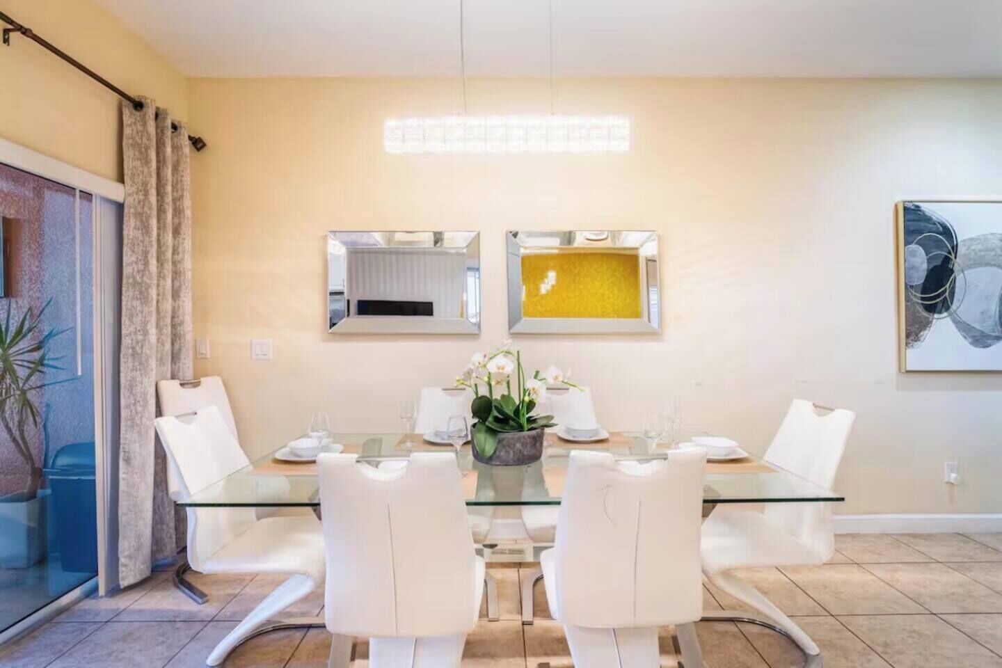 Un comedor moderno con una mesa de vidrio, sillas blancas y una planta en maceta.