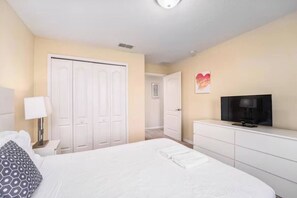 A hotel room with a bed, a TV, a dresser, and a closet. - Paradise Oasis| Stylish 4 Bed|Pool House (Kissimmee)