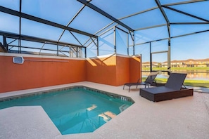 An indoor swimming pool with a glass ceiling, a lounge area with chairs, and a view of a residential area. - Paradise Oasis| Stylish 4 Bed|Pool House (Kissimmee)