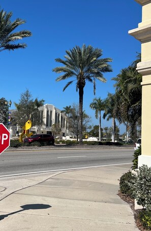 A street view with a stop sign, palm trees, and a building with a sign that reads 'MUNICIPAL'. - Bright 2-bedroom apartment with AC in brilliant Sarasota City Center ! (Sarasota)