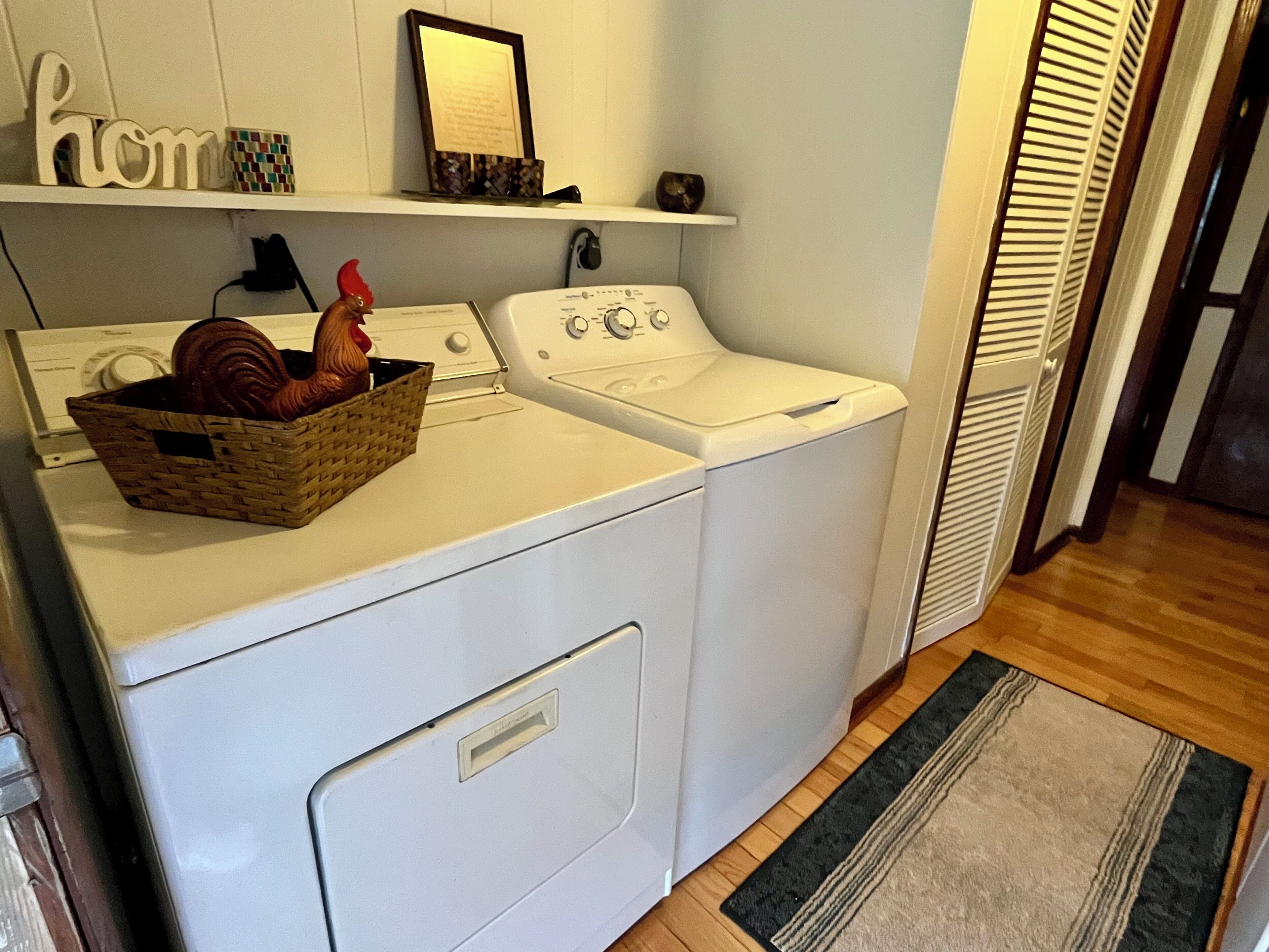 Un espace buanderie comprenant un lave-linge, un sèche-linge et un panier décoré d’un motif de coq.