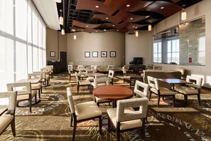 A spacious conference room with multiple tables and chairs, large windows, and a television screen.
