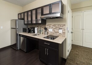 A compact kitchen with a refrigerator, microwave, stove, and dishwasher. - Accessible Queen Studio w/ Free Hot Breakfast (Saskatoon)