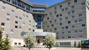 Un hôtel à plusieurs étages doté d’une cour intérieure, d’une statue et d’une enseigne indiquant les établissements Holiday Inn Express & Suites et Staybridge Suites.
