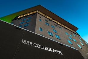 A building with '1838 COLLEGE DRIVE' signage, multiple windows, and a flat roof.