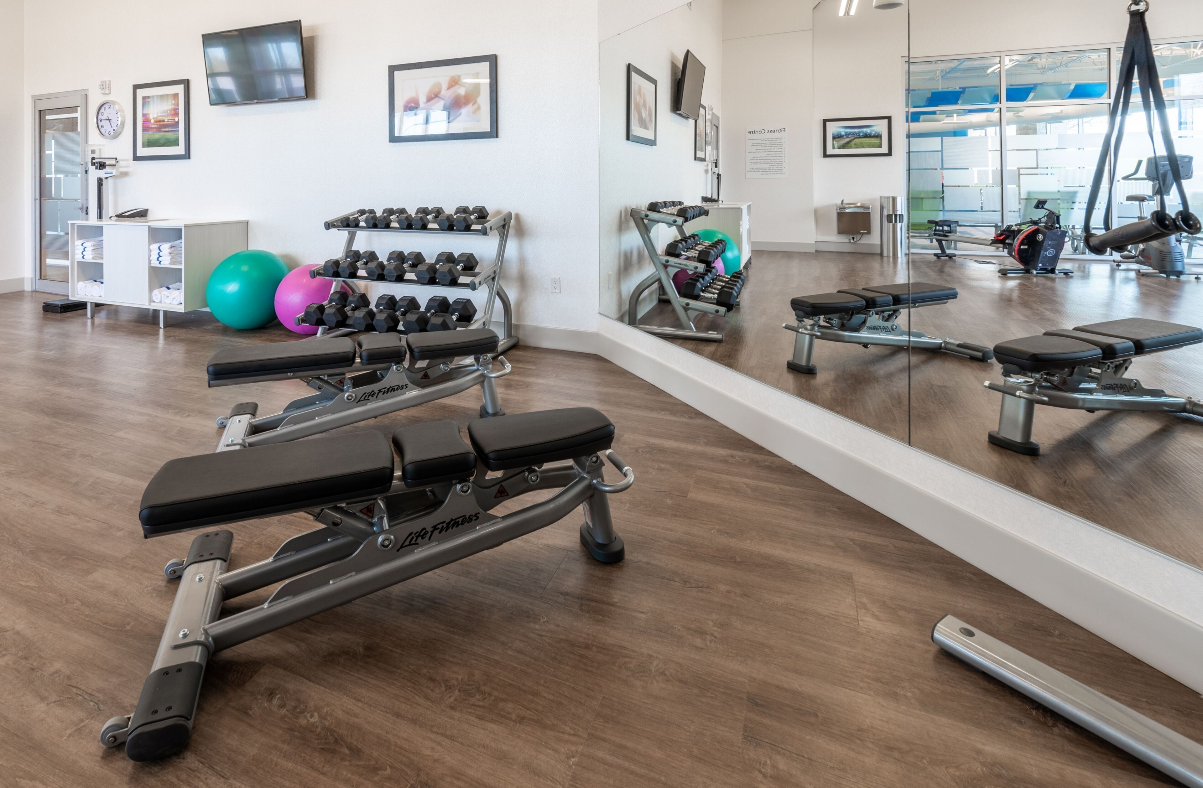 A gym with exercise equipment, a mirror, and a wall-mounted TV.
