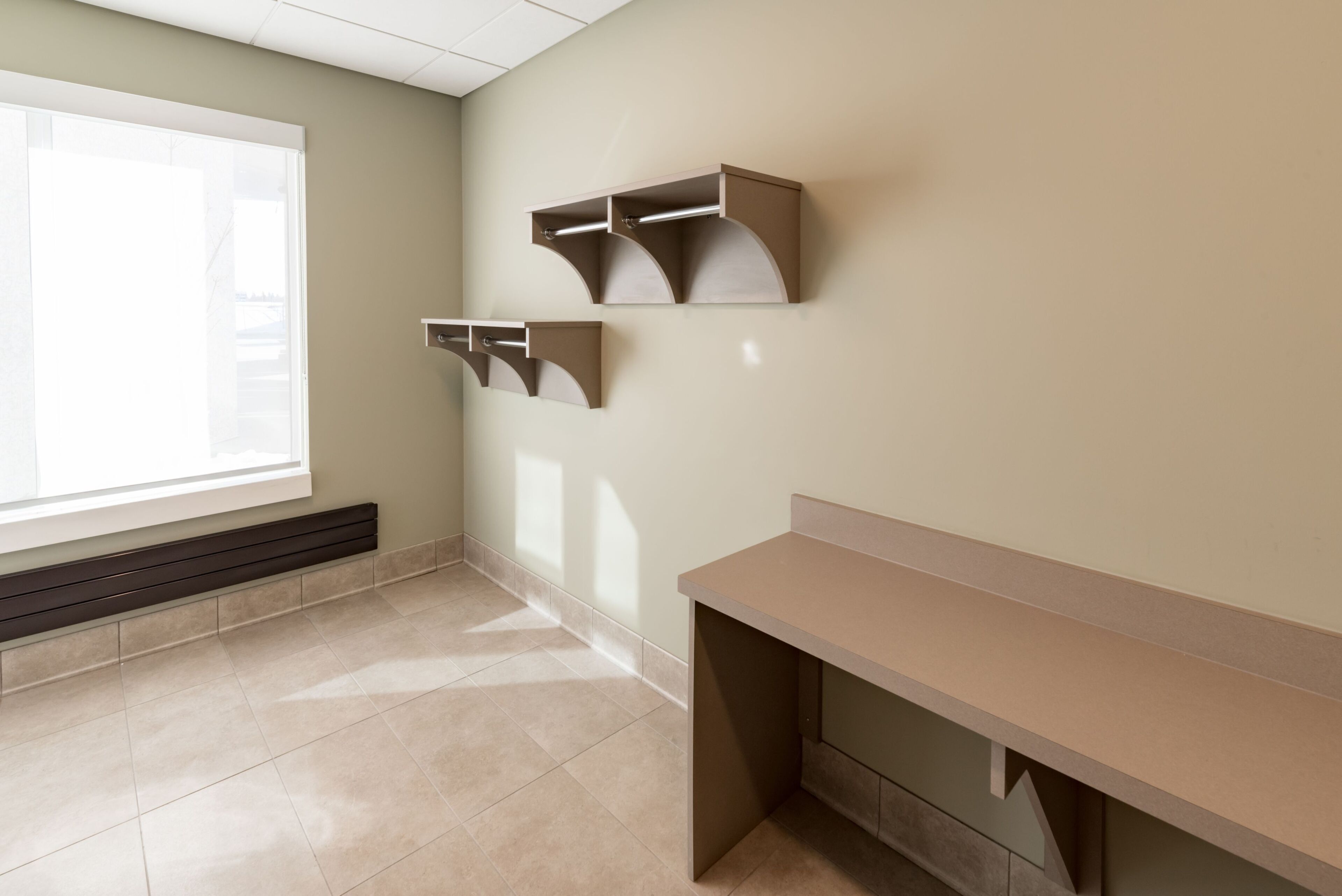 A room with a large window, a desk, and wall-mounted shelves.