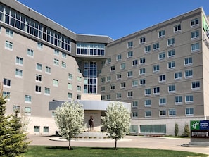 A multi-story hotel with a central courtyard, a statue, and a sign for Holiday Inn Express & Suites Staybridge Suites. - Studio Suite w/ Roll-In Shower | Free Breakfast (Saskatoon)