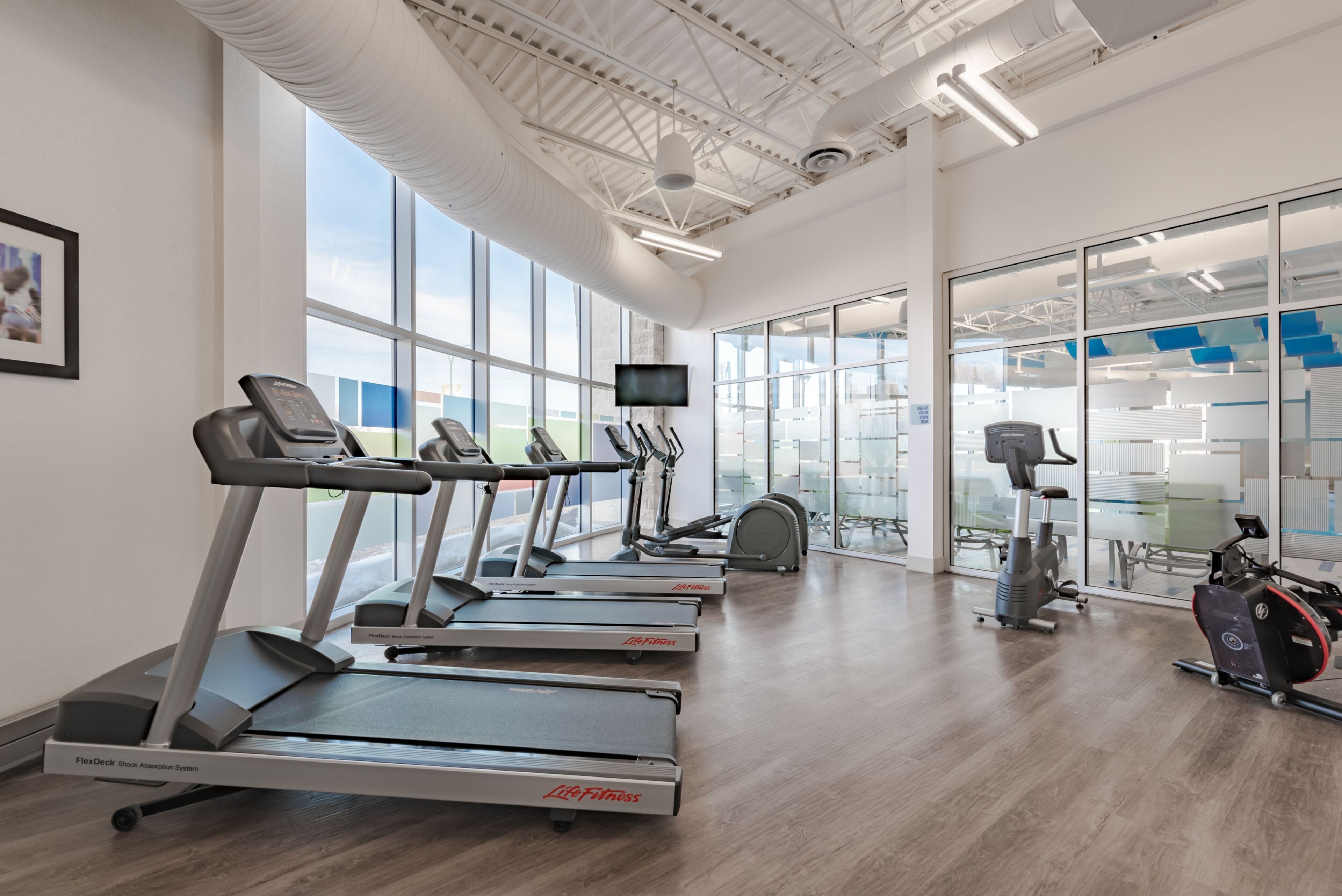 Ein Fitnessraum mit Laufbändern, Crosstrainern und einem Ergometer.