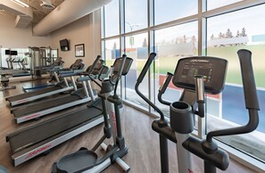 Une salle de sport équipée de tapis de course, de vélos elliptiques et de matériel de musculation.
