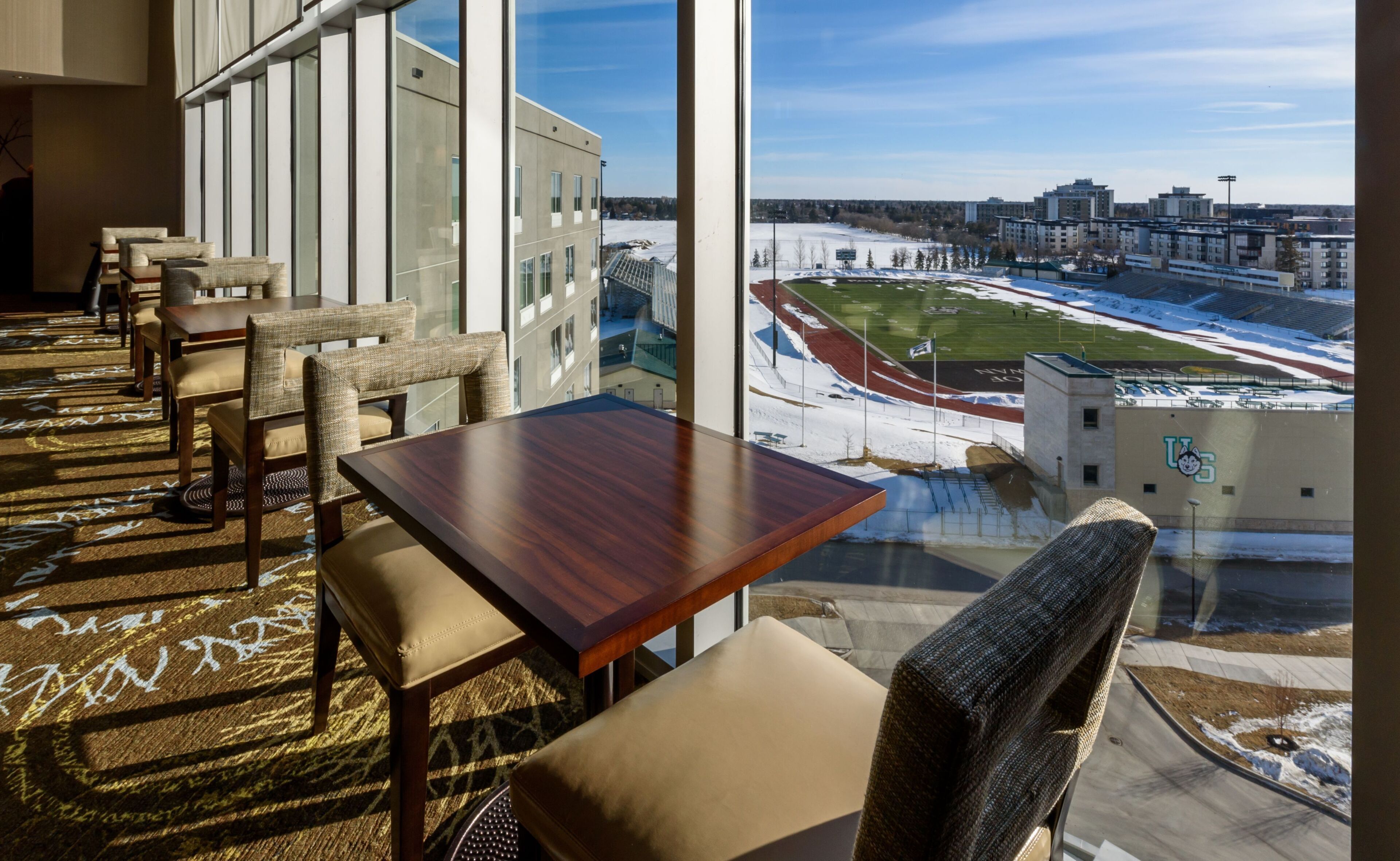 A hotel room with a large window overlooking a sports stadium and cityscape.