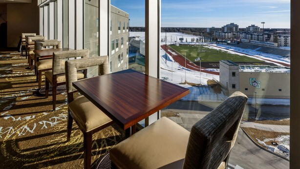 A hotel room with a large window overlooking a sports stadium and cityscape. - Studio Suite w/ Roll-In Shower | Free Breakfast (Saskatoon)