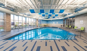Une piscine intérieure à l’eau claire, dotée de repères indiquant la profondeur et de panneaux de signalisation de sécurité.