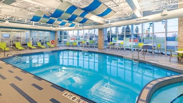 An indoor swimming pool with clear markings, sunshades, and seating areas.