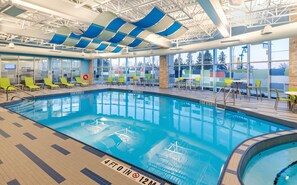 An indoor swimming pool with clear markings, sunshades, and seating areas.