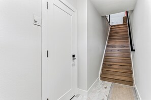 A hallway with a white door, a wooden staircase, and a textured mat at the bottom. - Playa Kas Waterfront Townhouse (Indian Rocks Beach)